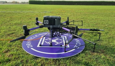 DRONICLE Drone on the landing pad next to grass during training