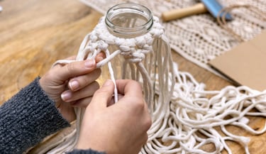 manos tejiendo en macramé usando una botella para sostener el tejido
