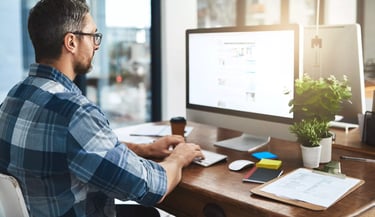 a man sitting at a desk with a computer and a coffee cup