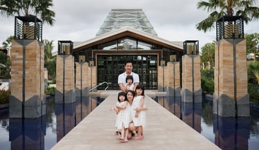 Family portrait at the iconic water reflection entrance of The Mulia Nusa Dua Bali during a Bali family photography session