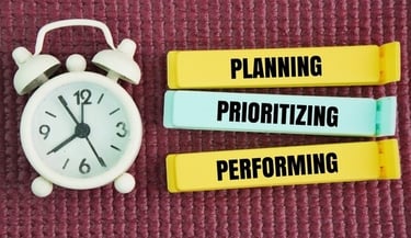White alarm clock next to labels for planning, prioritizing, and performing time management.