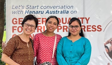 3 women in front of large placard