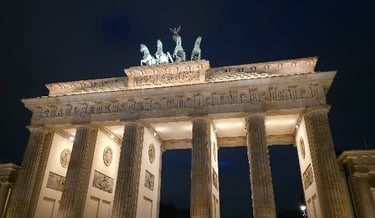 The Brandenburg Gate in Berlin illuminated at night, showing the Quadriga statue and neoclassical columns.