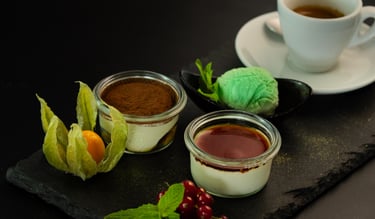 Tiramisu- und Panna-Cotta-Desserts in Gläsern serviert mit Minzeis und Espresso.
