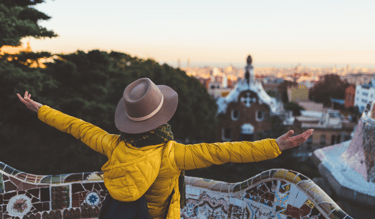 a woman in a yellow jacket and hat with her arms outstretched out