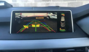 In-car dashboard screen showing live reversing camera view with coloured parking lines