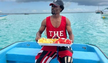 Local Zanzibar tour guide serving fresh fruits on a Mnemba Island day tour boat trip with tourists enjoying the journey