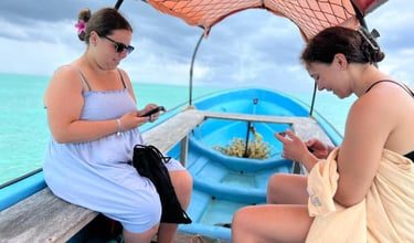 Two tourists relaxing on a boat during a Mnemba Island Zanzibar day tour, preparing for snorkeling adventure