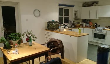 Una cucina con tante cose sul ripiano e un tavolo con dei fiori sopra