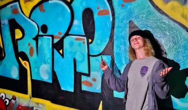 young person standing in front of a mural with Reid's name