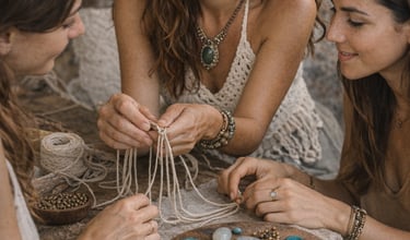 Tres mujeres creando joyería artesanal con macramé y piedras