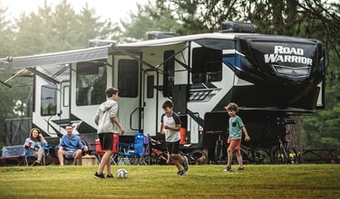 a group of people playing soccer in a field near an RV
