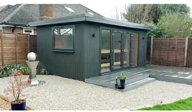 Modern dark grey insulated garden office with glass doors and composite decking