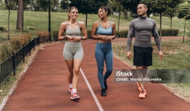 three people running on a track with a woman in a sports bra