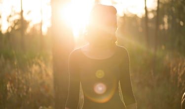 woman in forest with sun glistening representing subtle energy healing