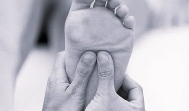 Une personne masse un pied et une jambe  / réflexologie