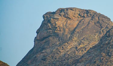 a bird flying over a mountain with a blue sky