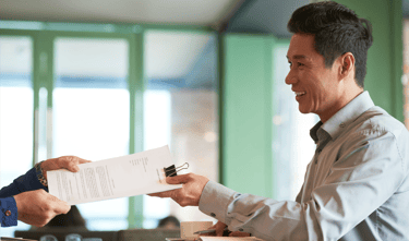 a man in a suit and tie is handing a permit document to a woman