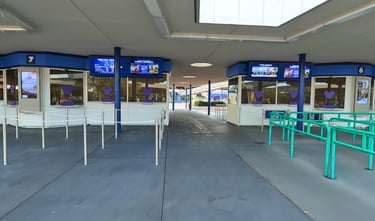Disney World ticket windows with digital screens and queuing ropes at a park entrance