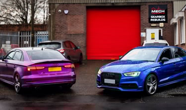 Purple and blue Audi S3 cars parked outside a professional gearbox rebuild garage facility.
