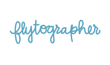 Flytographer brand logo in blue cursive script typography against a solid black background.