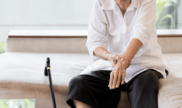 a woman sitting on a couch with a cane and wrist pain sarcopenia