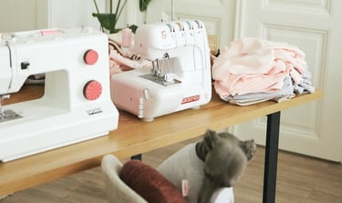 a cat sitting on a table with a sewing machine