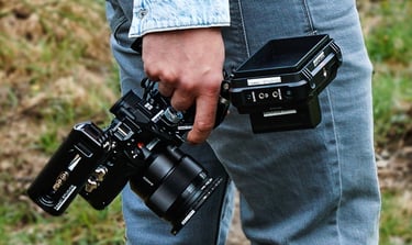 Mann in blauer Jeans, draußen, mit Kamera Rig in der Hand, von hinten