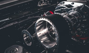 Close-up of a high-performance chrome supercharger with a drive belt on a custom car engine.