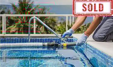 Person servicing a swimming pool with cleaning equipment, labeled "SOLD".