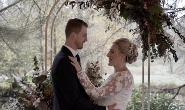 a bride and groom standing in front of a wedding arch