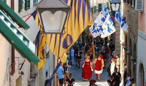 Traditional historical parade with colorful flags in the medieval streets of Montalcino.