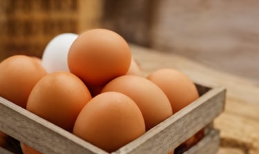 Close up photo of brown eggs in a wooden tray.