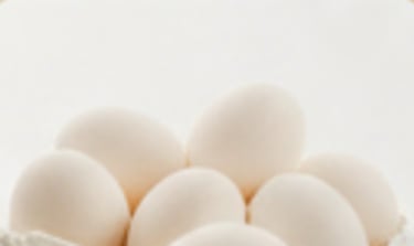 Close up photo of white eggs stacked together.