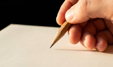 Main qui tient un crayon de papier au-dessus d'une feuille blanche