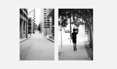 Black and white street photography showing an empty city road and a person walking on a sidewalk.