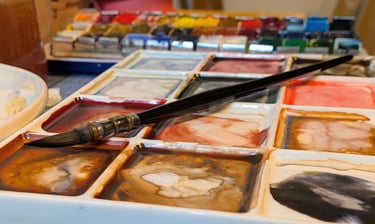 Waterverf palet met penseel en aquarel napjes, gemengde kleuren op een bord