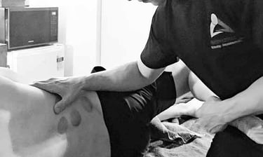 Male massage therapist performing Myofascial Stretching of the leg and back