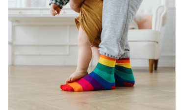 Adult feet with baby feet standing on top of them