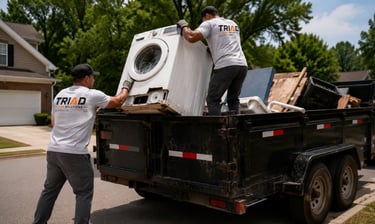 Professional junk removal team loading a washing machine into a disposal truck.