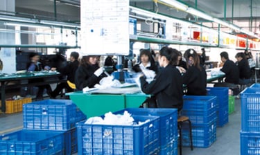 Factory workers in uniform assembling bath products on industrial production line with blue crates.