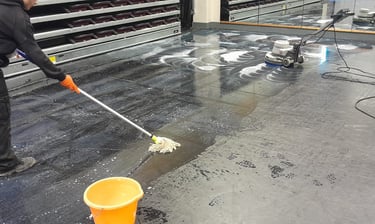 a man is cleaning a floor with a broom and bucket