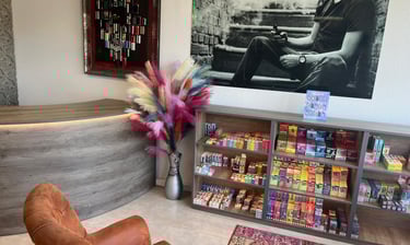 A modern vape shop interior featuring shelves of colorful e-liquids, a leather armchair, and wall art.