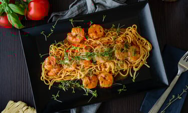Elegante schwarze Platte mit feinen Spaghetti in einer köstlichen Scampi-Garnelen-Sauce,