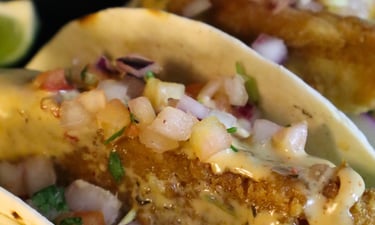a plate of fish tacos with a lime wedged fish tacoil