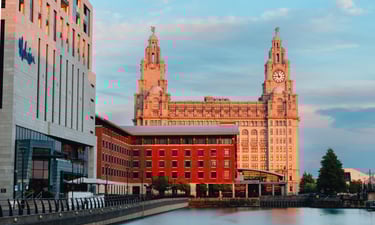 The Royal Liver Building at Liverpool's Pier Head waterfront during a golden hour sunset.