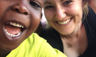 Bild von Nadja mit einem fröhlichen Kind aus Uganda