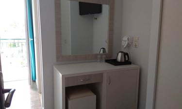 a small white vanity with a mirror and a coffee maker