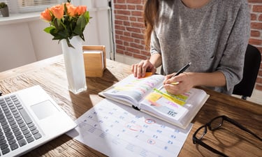a woman sitting at a desk with a notebook and a notebook