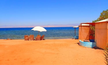 Bedouin Star beach with bamboo chairs, umbrella, and a front-line bungalow by the Red Sea